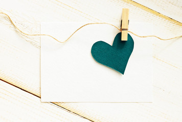 Blue heart pinned with little blank note message, top view, retro toned, pastel colors.