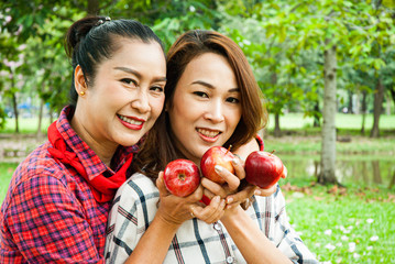 Beautiful family woman smile holding and eating apples at park.