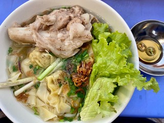 Vietnamese typical street food wonton pork soup bowl with pork bone and vegetable