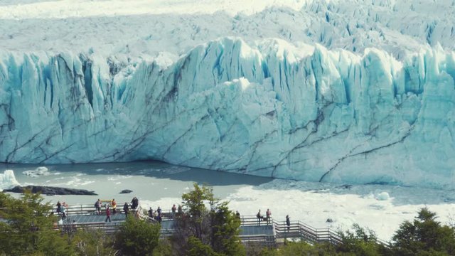 People on the lookout  enjoying the view of the Majestic wall of Perito Moreno Glacier. Glacier cracking and falling over the lake, climate change. 4k