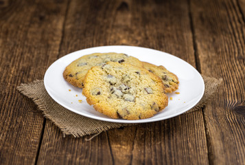 Old wooden table with fresh Chocolate Chip Cookies (close-up shot; selective focus)