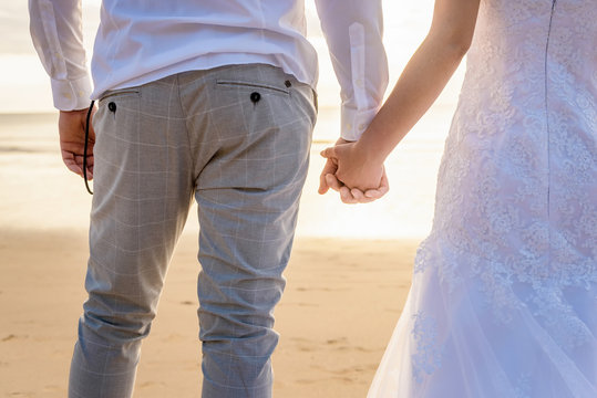 Wedding couple holding hands with sunset on background