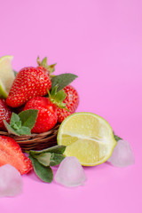 Fototapeta na wymiar Fresh strawberries with lime, mint and ice on a pink background. Ingredients for Strawberry Mojito.