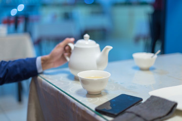 Business man pours tea in a cafe or restaurant