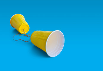 Comunication Yellow Plastic cup with string isolated on blue background