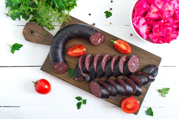 Morsilla - blood sausage. Pieces of Spanish black pudding on a wooden cutting board on white...