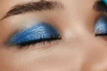 Close up and cut view of afro american skin with blue metal color eyeshadows. Stylish eyebrows and...