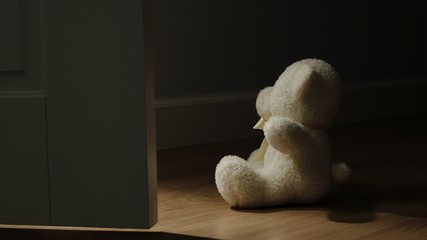 Plush Bear Toy Sitting On The Floor In A Dark Room
