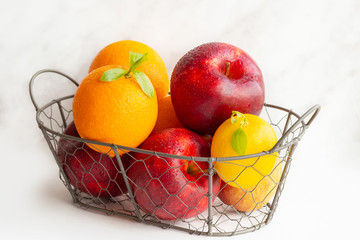  A basket of fruits. A set of vitamins. A metal basket with apples and oranges. Vitamin C. Lemon. Vegetarian, vegan food. Proper nutrition. Carbohydrates. A healthy set. Citrus fruits.apples.