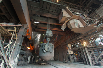 Day view of the oxygen-converter shop. A crane pours cast iron from a ladle into a converter in a kiosk-converter shop.