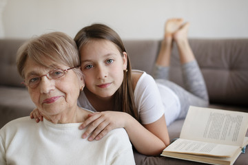 Obraz na płótnie Canvas Grandmother with granddaughter reading books at home