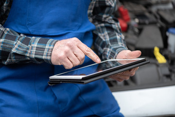 Mechanic using digital tablet for checking car engine