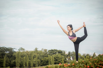 Young Asian woman practicing yoga in the park