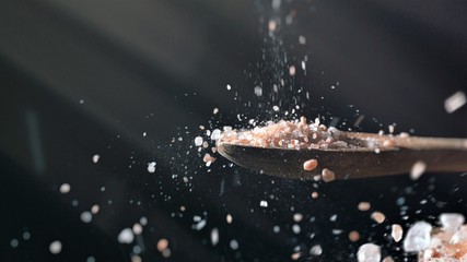 Close up of himalayan salt pouring from above on wooden spoon recipe seasoning ingredients - obrazy, fototapety, plakaty