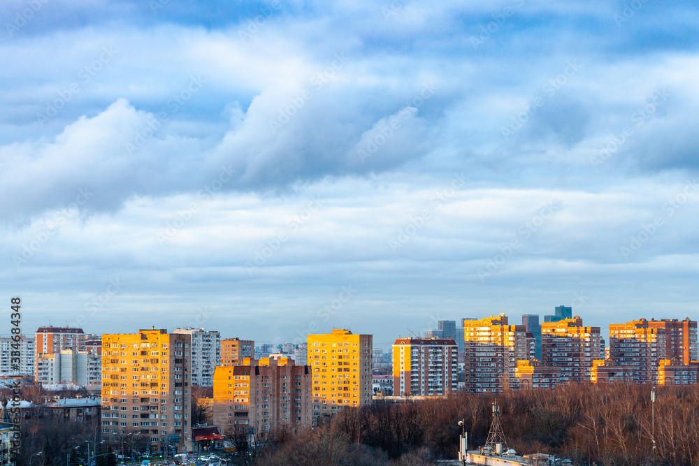 Wall mural blue clouds over urban houses at spring sunset