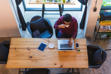 Top view of Young asian freelancer working from home and using tablet while sitting the wooden...