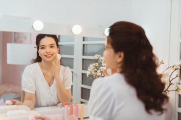 Woman cleaning face with white pad. Beautiful girl removing makeup white cosmetic cotton pad.