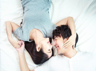 Portrait of pretty young asian couple with happiness. asia man and woman lay on bed facing together with big smile hand cover face each other. © mkitina4