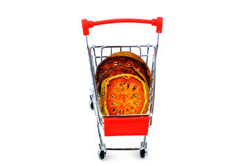 Dried bael fruit slices in red shopping cart isolate on white background.