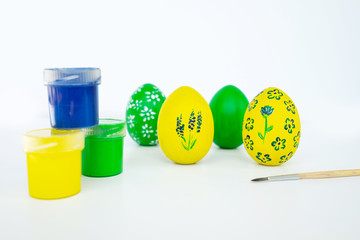 The concept of celebrating Easter. Workplace with cans of paint and colored painted eggs on white background. Isolated