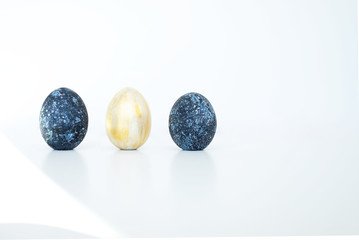 The concept of celebrating Easter. Colored cosmic dark blue with white dots and golden painted eggs on white background. Copy space. Isolated