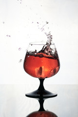 Glass of alcohol splashing with ice