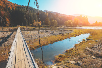 Wooden hanging rope bridge over mountain river