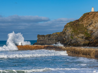 A large wave hitting the coast at Portreath, Cornwall, with the cliffs in the background