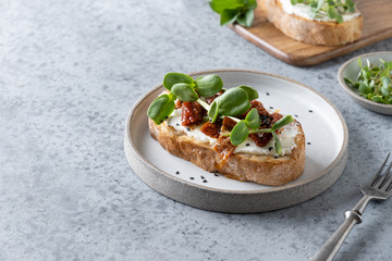 Sandwich on toast with fresh radish microgreen and cream cheese on grey background. Close up.
