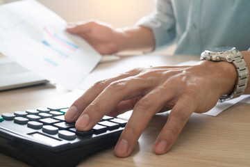 Businessmen sit and press the calculator to calculate and predict the company's power output according to the previous statistics held.