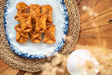  Top view of typical sweets of Spanish gastronomy on rustic wooden table and polka dot plate (Pestiños)