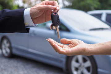 The male car dealer is delivering the keys to the woman bought or rented the car. sale and rental...