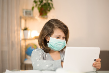 Schoolgirl in face mask with white tablet during her online home lesson. Online concept of school education and social distance during quarantine, self-isolation, digital concept. Distance Learning