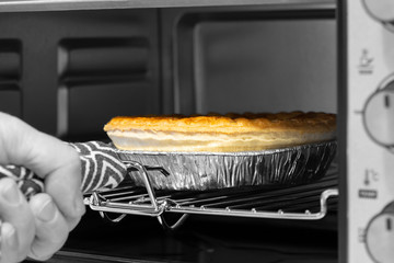 Steak and ale pie cooked in an electric oven grill being taken out by a man with a metal handle...