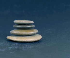 Fototapeta na wymiar Stacked rounded sea stones on blue surface, Small polished pebbles stack on blue background