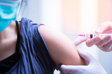 close up doctor's hand injecting for vaccination in the shoulder woman patient.Vaccine for protection HPV (Human Papillomavirus) infection.Vaccination for coronavirus treatment.