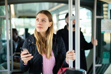 Woman using phone in city bus