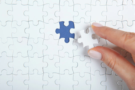 Collect puzzle. Hand and puzzle pieces on the table
 - Powered by Adobe