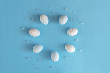 Festive Easter circle frame. Beautiful panted eggs polka dots and stripes with beads on pastel blue background with copy space. Nature celebration design. Flat lay, Top view.