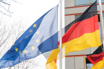 German and European Union flags waving against cloudy sky
