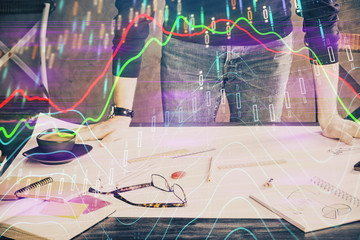 Multi exposure of man standing and planing investment with stock market forex chart.
