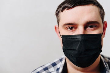 man in a shirt in a black medical mask on a gray background