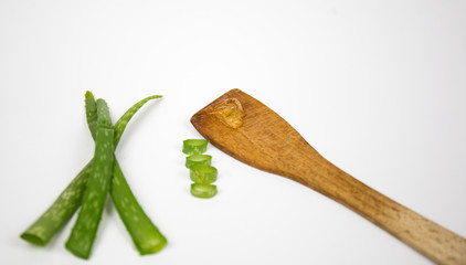 Aloe vera fresh leaves with slices and gel on wooden spoon. isolated over white. Aloe vera is a popular medicinal plant that is used for health and beauty.