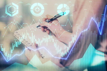 Multi exposure of hands making notes with forex chart huds. Stock market concept.