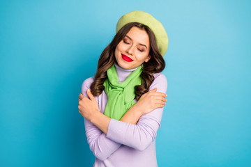 Closeup photo of cute lady red lips eyes closed hugging herself peace inner harmony concept wear green beret hat purple turtleneck scarf isolated blue color background