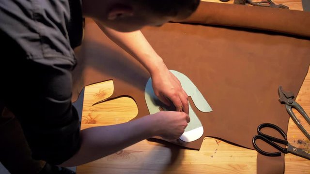 Man draws a shoe with pencil on a table 
