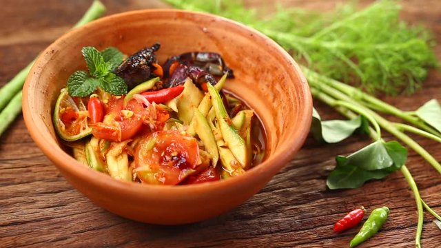 Thai food: Som Tam is popular Thai food. Mango salad with dried shrimp, salty crab, chili, tomato and spicy herbs. Served with vegetables. Still life shoot in studio, Clean food good taste concept.