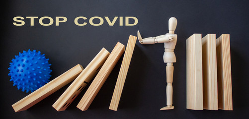 COVID-19 Pandemic Coronavirus concept. Wooden model of man stopping wooden domino blocks. Inscription covid19.