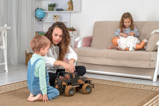 Young mother or nanny with two little children spend time together at home