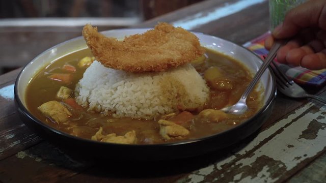 Japanese food: Tonkatsu on steamed Japanese rice with curry on table. Clean food concept. Toned image. Selective focus and free space for text. Low light in restaurant.